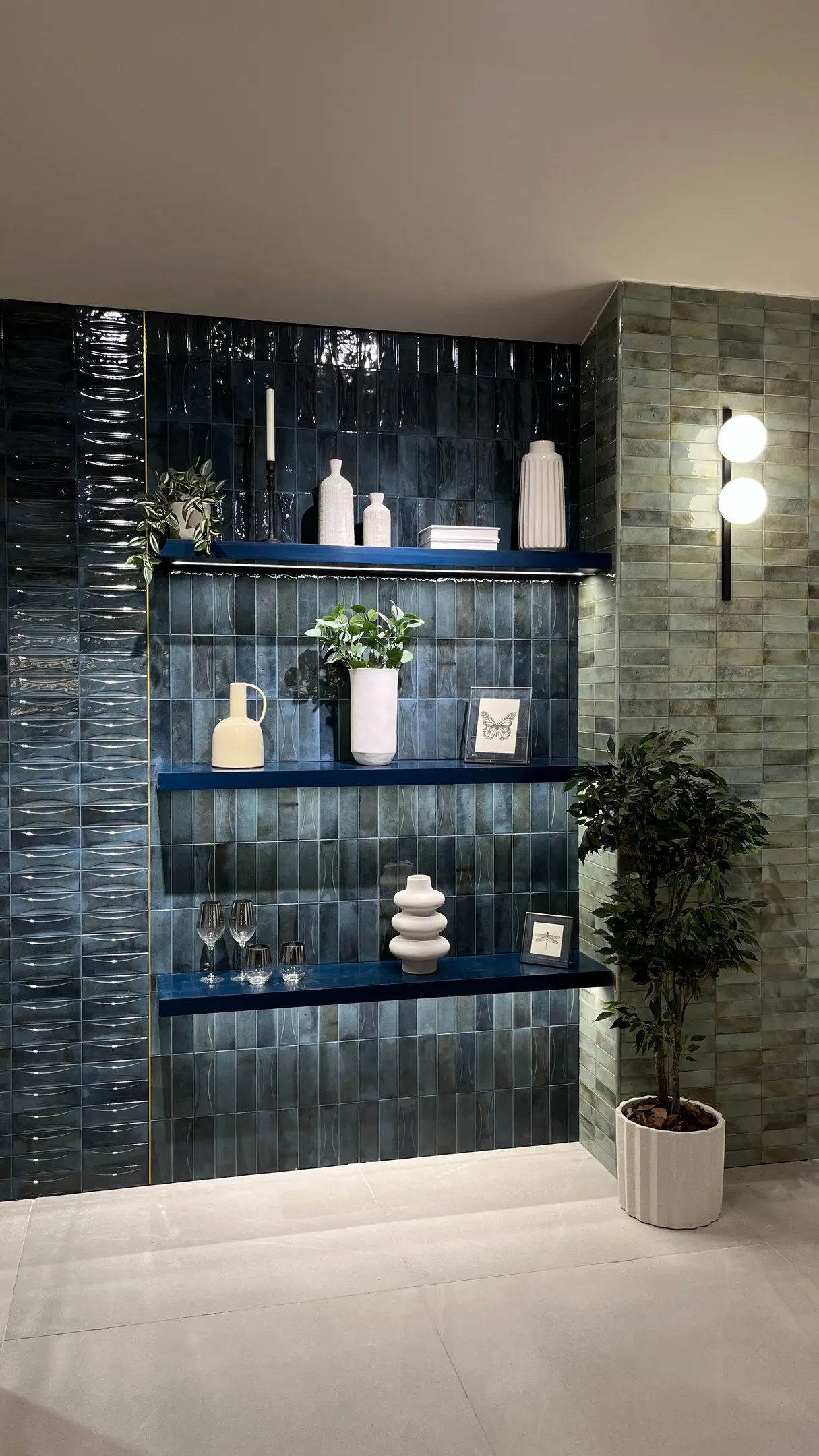 Stand en Coverings con pared de azulejo verde oscuro y estantes