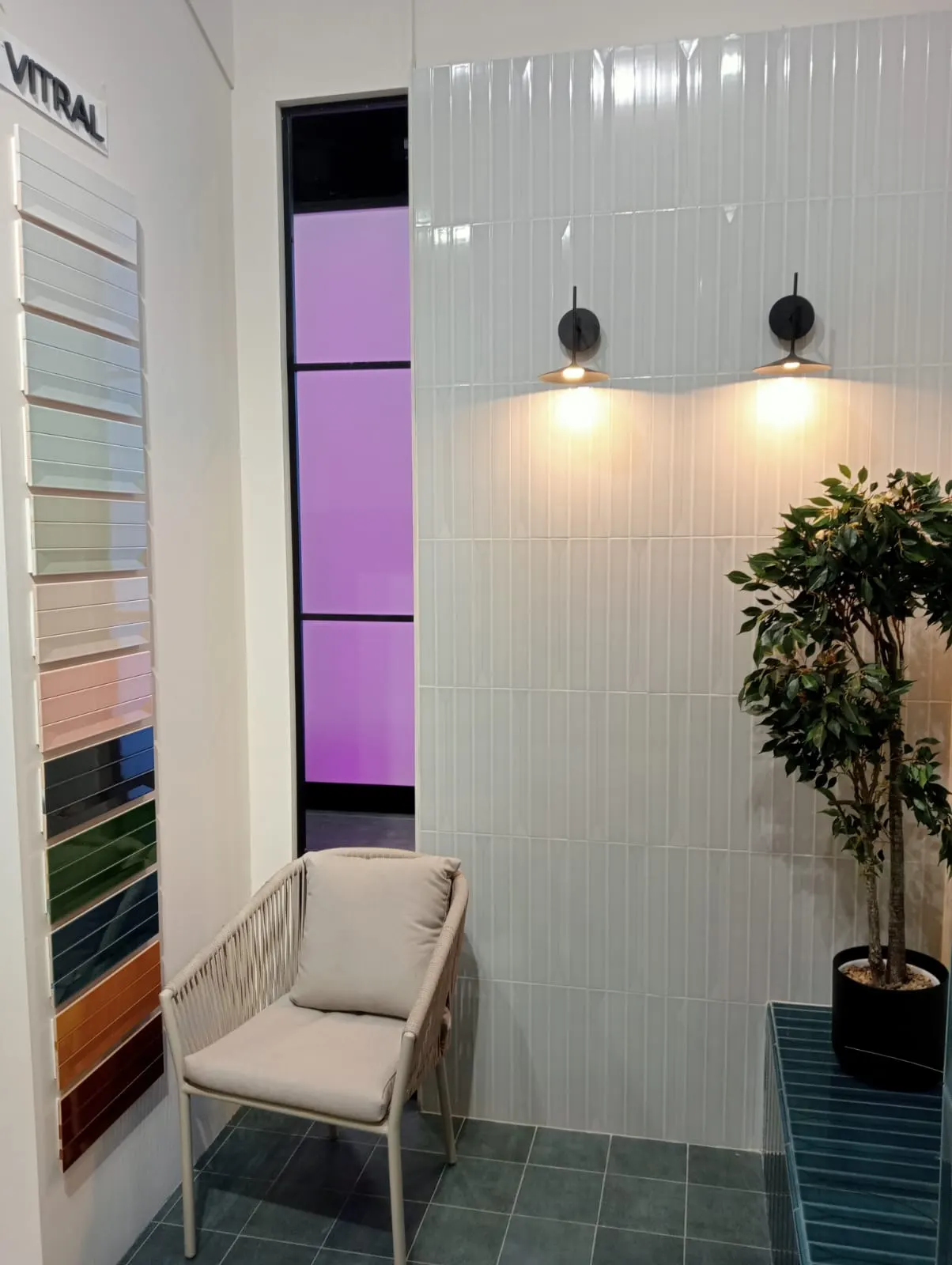 Exposición con pared de azulejo blanco vertical y muestrario de colores